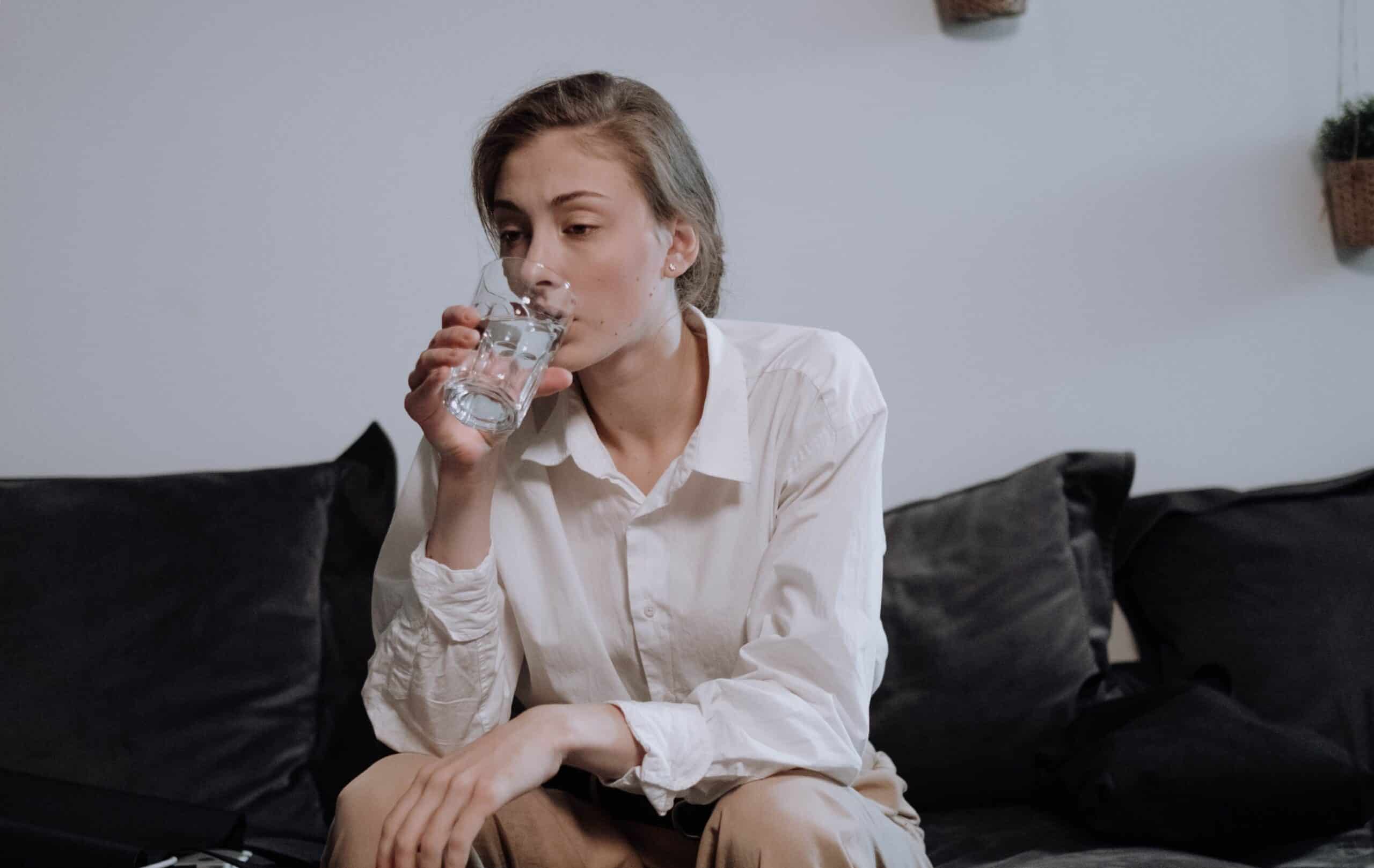 locataire assise souffrant de la canicule en buvant un verre d'eau